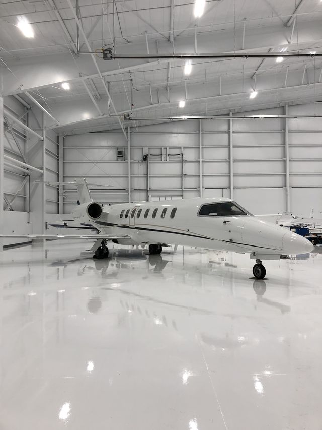 Finished white floor beneath aircraft in an aerospace maintenance hangar