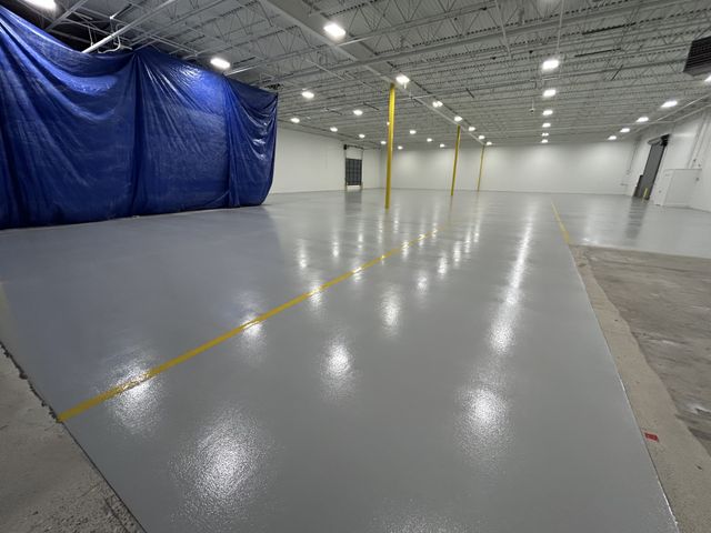 Finished epoxy broadcast floor with yellow traffic striping at Milgard manufacturing facility