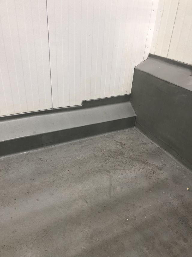 Sealed transition detail between insulated metal panels and concrete curb in a potato processing facility